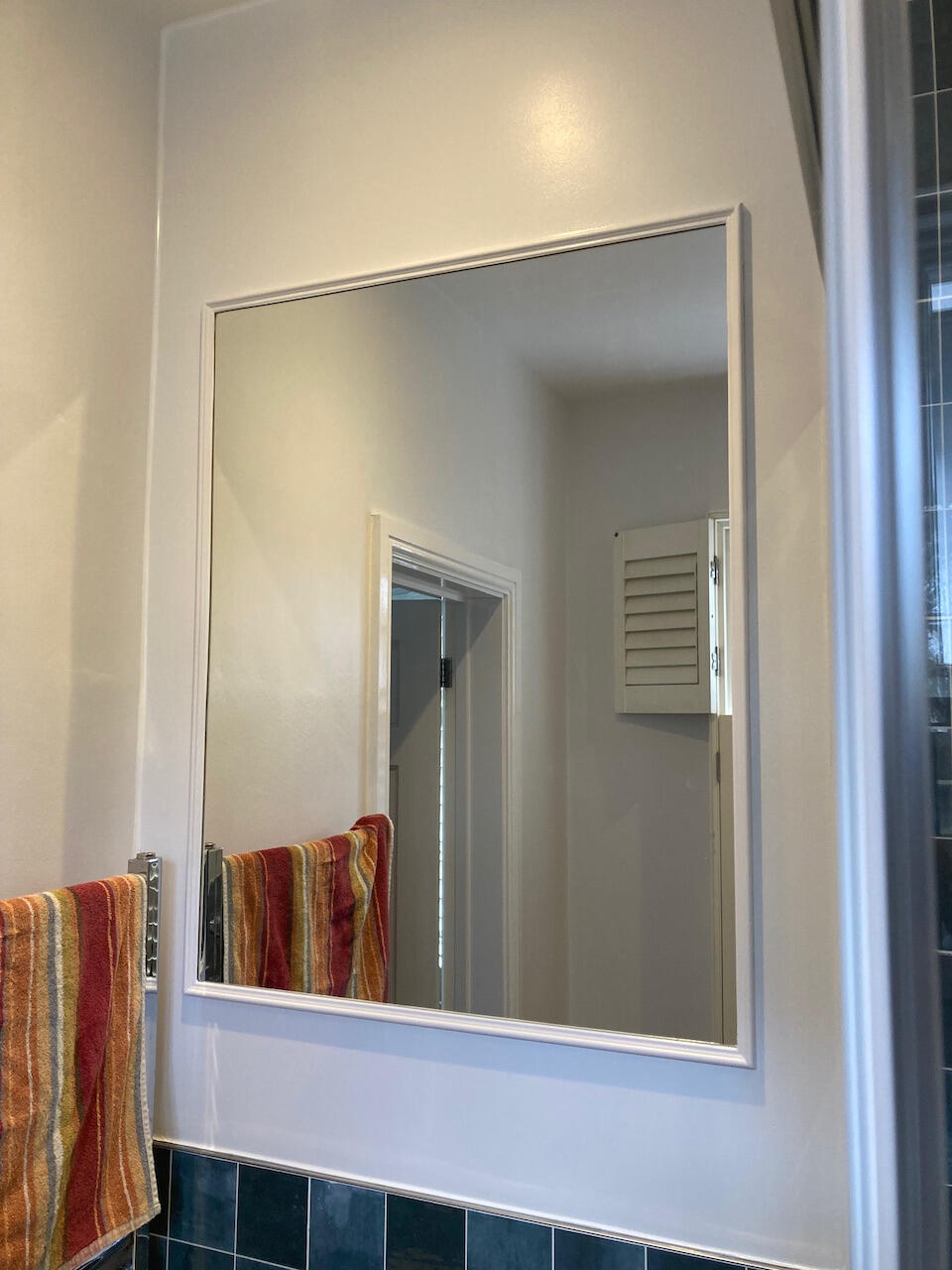 Finished bathroom mirror installation with a fitted wooden frame for a clean final look